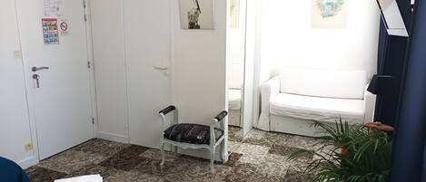 A room with a bed, a chair, a sofa, a small table, and a potted plant.
