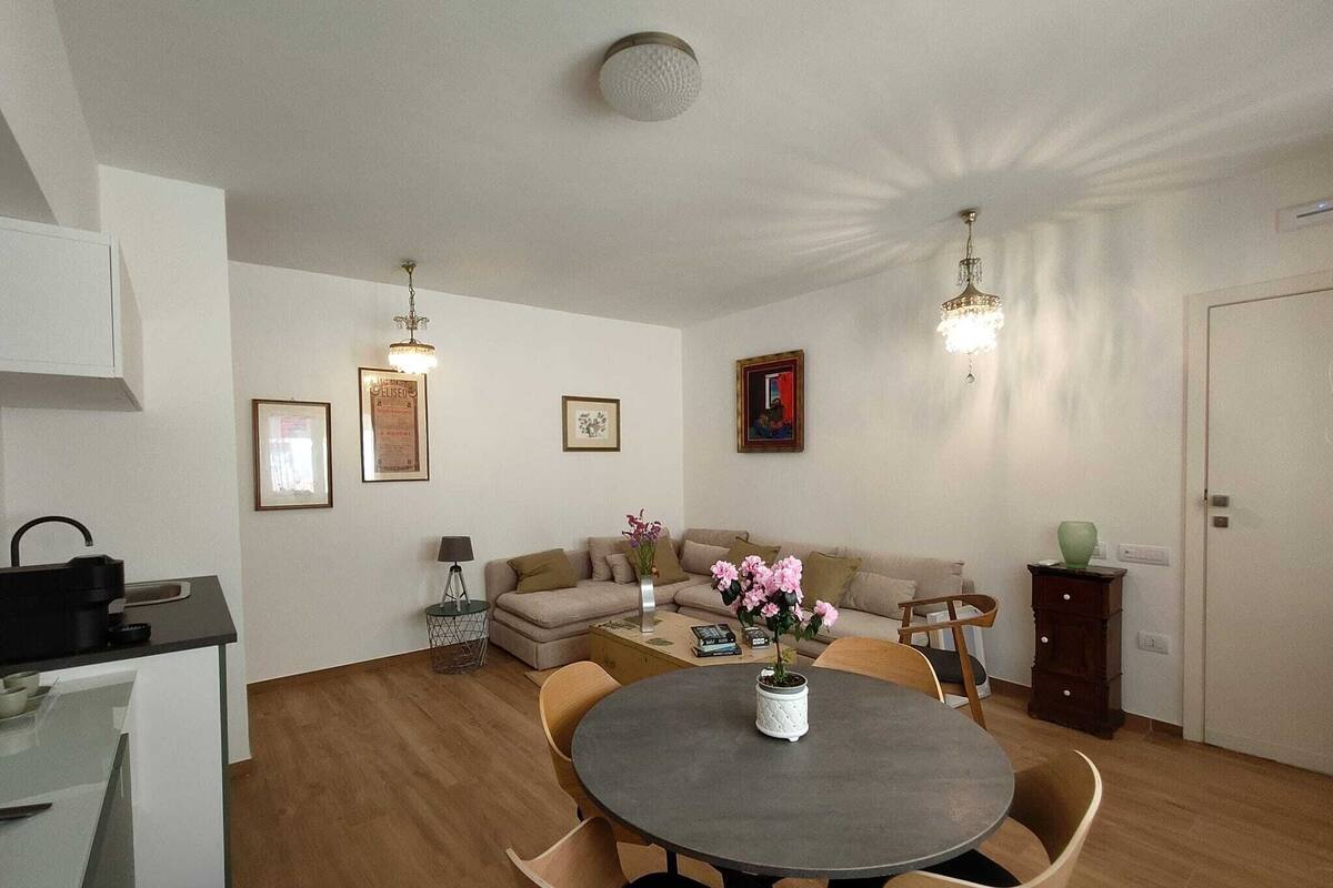 Un salon moderne comprenant une table à manger, un canapé et un coin cuisine équipé d’une machine à café.