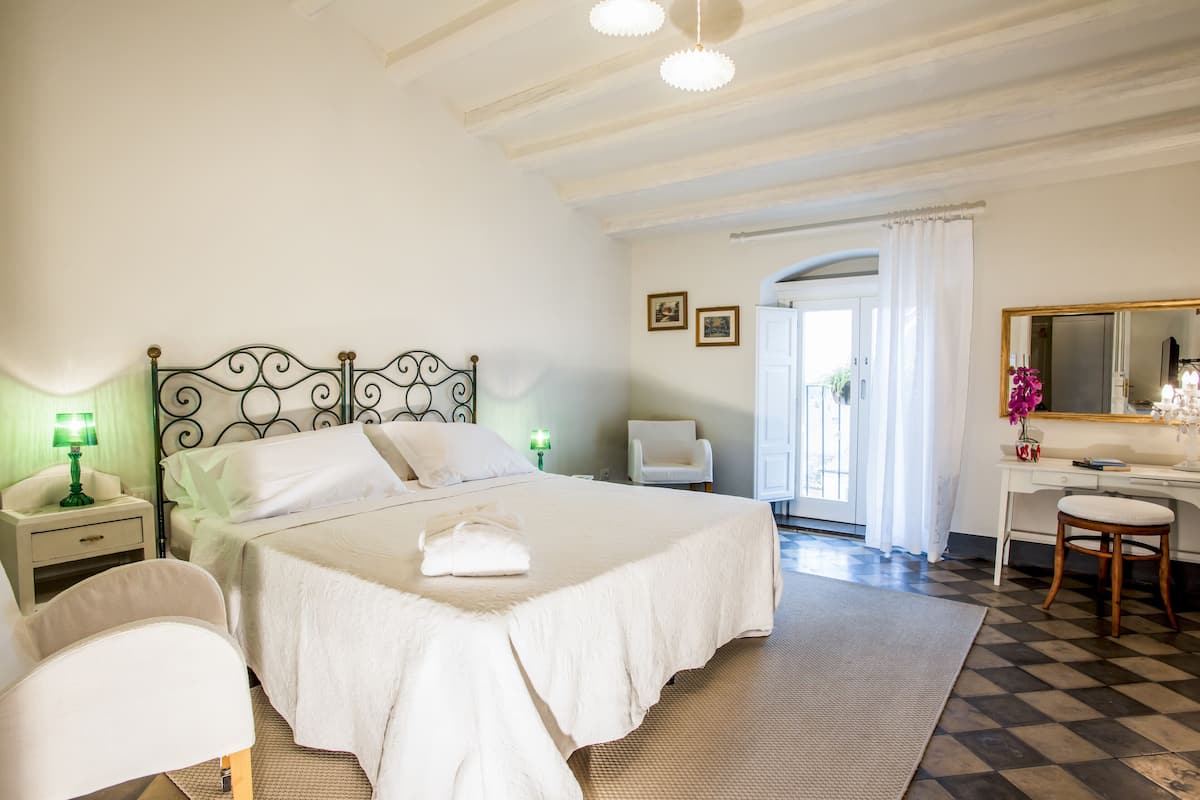 Une chambre à coucher comprenant un lit, des tables de chevet, un bureau, une chaise et un miroir.