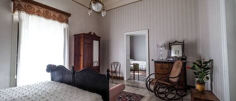 A bedroom with a bed, a rocking chair, a dresser, and a mirror.