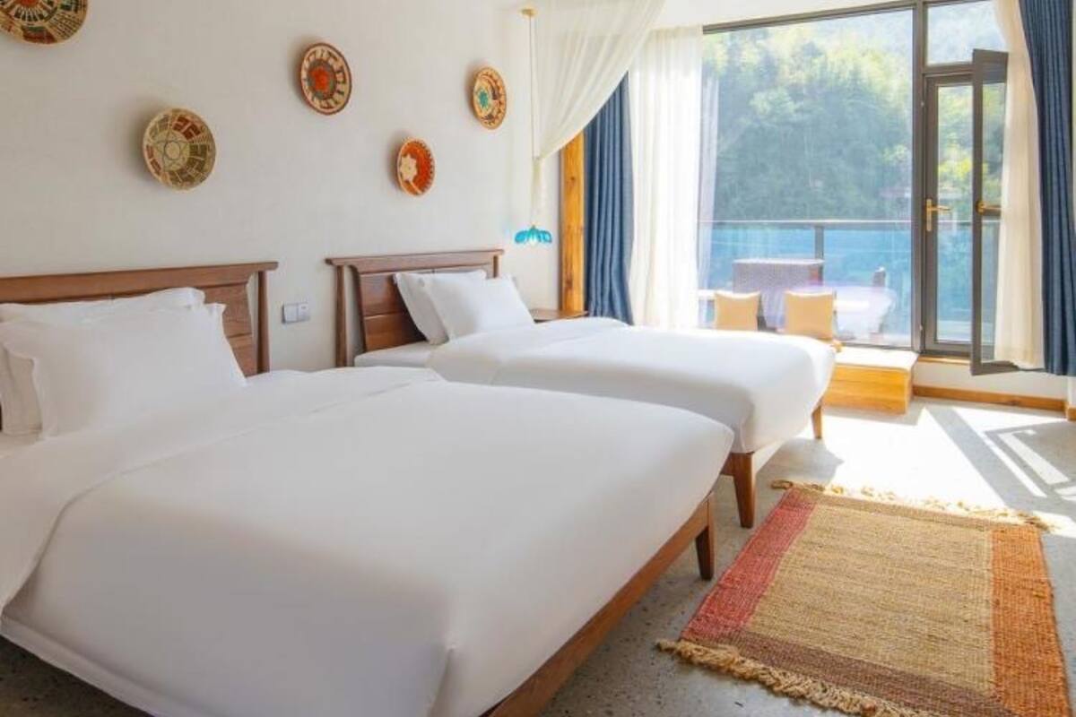 Une chambre d’hôtel avec deux lits, un balcon offrant une vue agréable et des assiettes décoratives accrochées au mur.