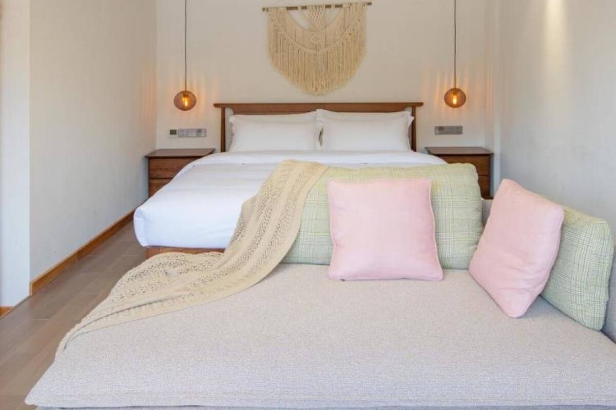 Une chambre à coucher avec un lit, des lampes de chevet, une décoration murale en macramé et un luminaire circulaire.