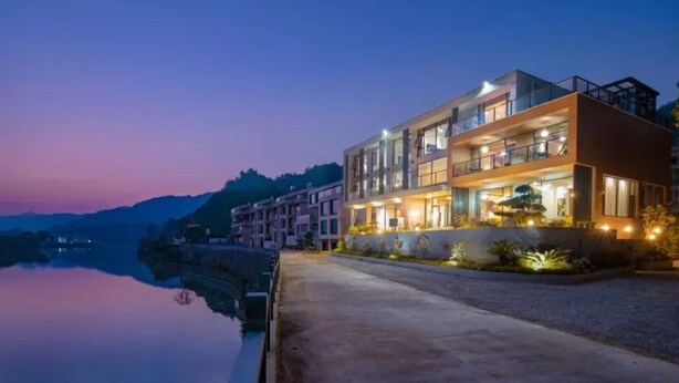 Ein modernes Hotel mit mehreren Etagen, großen Fenstern und einer gut beleuchteten Fassade.