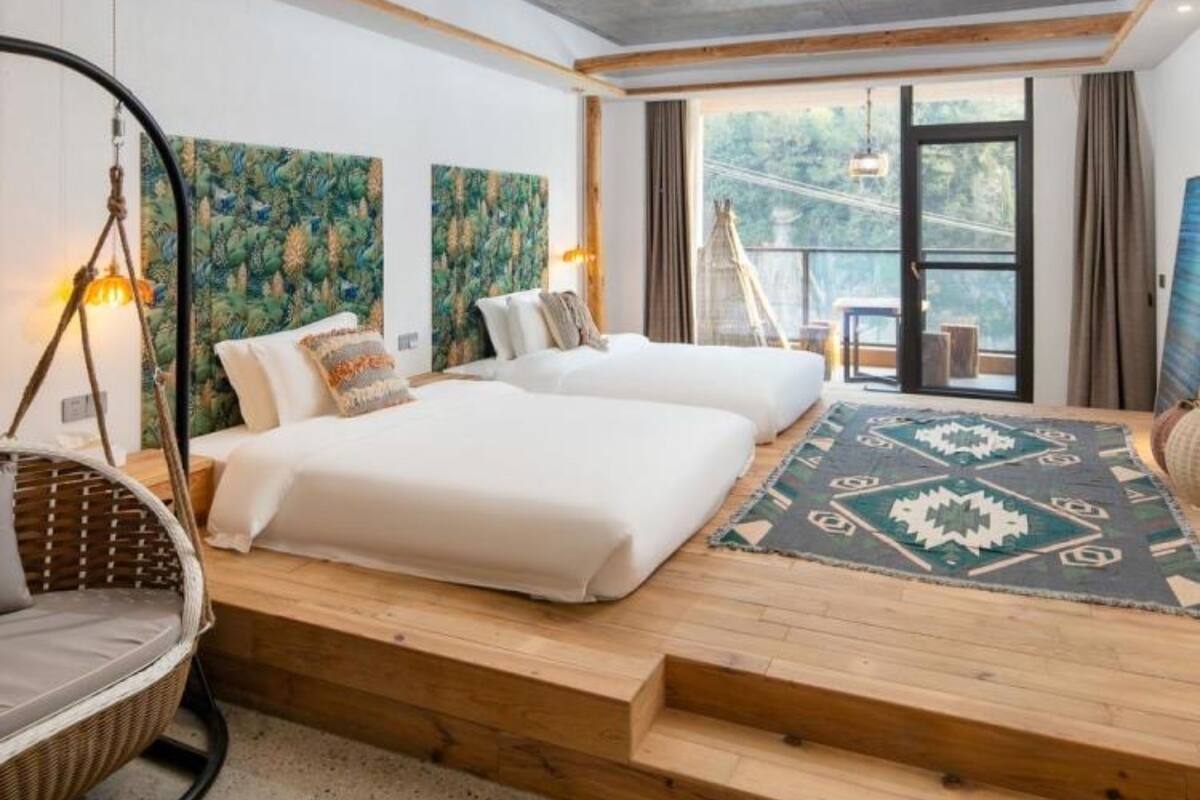 Une chambre d’hôtel moderne avec un grand lit, un fauteuil suspendu et une vue sur l’extérieur.