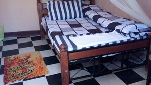 A bed with a checkered floor, a mosquito net, and a patterned rug.