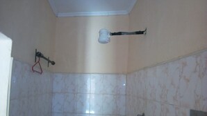 A bathroom with tiled walls, a shower, and a toilet.