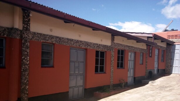 A row of buildings with a consistent architectural style, featuring a mix of red and beige walls, and a flat roof.