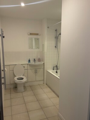 Ein Badezimmer mit Toilette, Waschbecken, Spiegel und Dusche.
