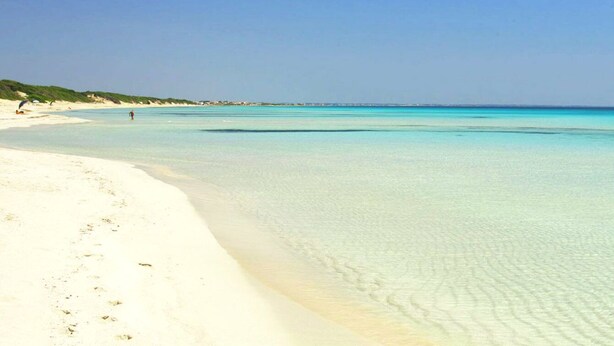 En strand med krystalklart turkis vand og hvidt sand.