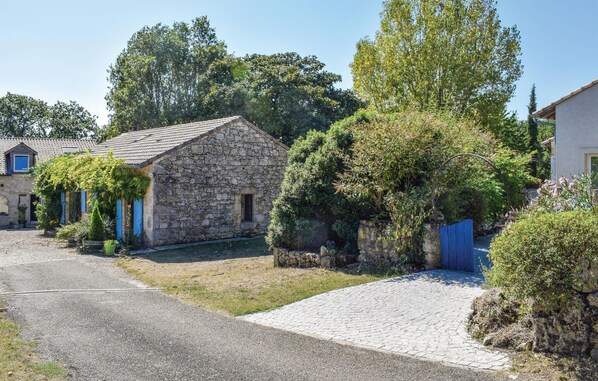 A stone building with a tiled roof, surrounded by greenery and a gravel driveway. - Gorgeous home in Sembas with swimming pool (Sembas)