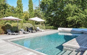 A swimming pool with lounge chairs and umbrellas, surrounded by trees. - Gorgeous home in Sembas with swimming pool (Sembas)