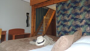 Une chambre avec un lit superposé, un escalier en bois, un mur à motifs et un lit avec un couvre-lit et un oreiller.