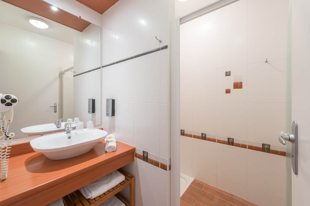 Un baño con dos lavamanos, un espejo, toallero y zona de ducha.
