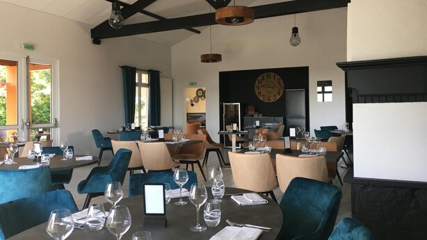 Un restaurant doté de nombreuses tables, de chaises et de luminaires suspendus.