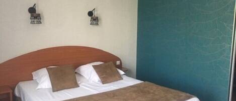 A neatly made bed with a wooden headboard, white bedding, and two brown pillows.