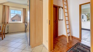 Une cuisine avec des meubles de rangement en bois, un radiateur et une fenêtre avec des rideaux.