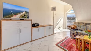 Una sala de estar moderna con televisor, radio, sofá y balcón con vistas.