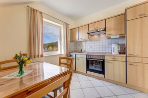 Une cuisine moderne avec des meubles en bois, une table à manger avec des chaises et une fenêtre avec des rideaux.