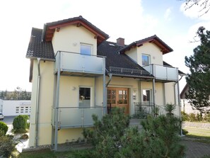 Une maison à deux étages avec un balcon, une porte en bois et un petit porche.