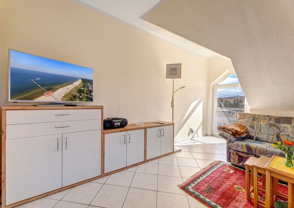 A modern living room with a TV, a radio, a sofa, and a balcony with a view.