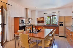 A modern kitchen with a central island, stainless steel appliances, and a dining area with chairs.