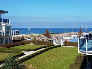 A marina with boats, a clear blue sky, and a well-maintained lawn with hedges. - (147) 2-room apartment - apartment complex Residenz Am Yachthafen (Kühlungsborn)