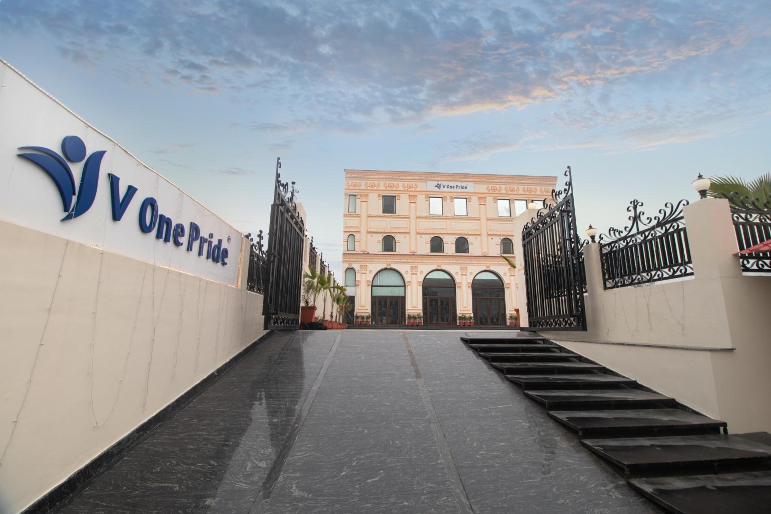 Entrada de un edificio con un letrero que dice “One Pride” y un acceso con portones.