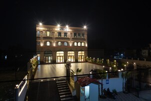 Un edificio de varios pisos con una entrada central, iluminado por varias luces.