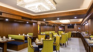Un restaurante con cabinas y mesas altas, paneles de madera y una lámpara de araña.