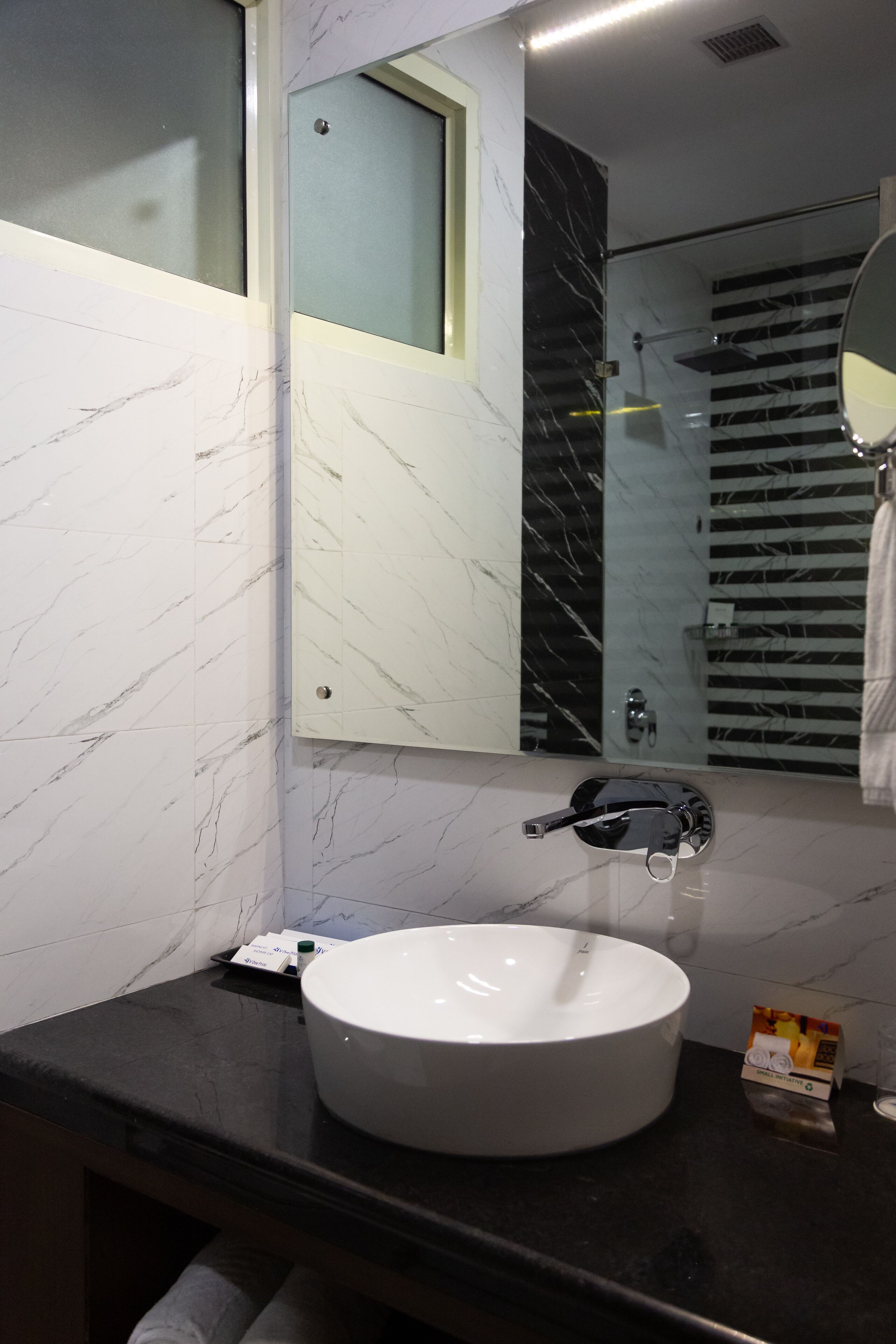 A modern bathroom with a white sink, a mirror, and a glass shower enclosure.