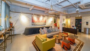 A modern hotel lobby with a sofa, chairs, a coffee table, and a reception desk. - No. 8 Art Hotel (Shanghai)