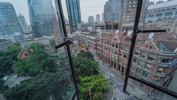 A cityscape with a mix of modern and traditional architecture, including high-rise buildings and historic buildings with red brick facades. - No. 8 Art Hotel (Shanghai)