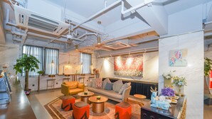 A modern hotel lobby with a sofa, armchairs, and ottomans arranged around a central coffee table. - No. 8 Art Hotel (Shanghai)