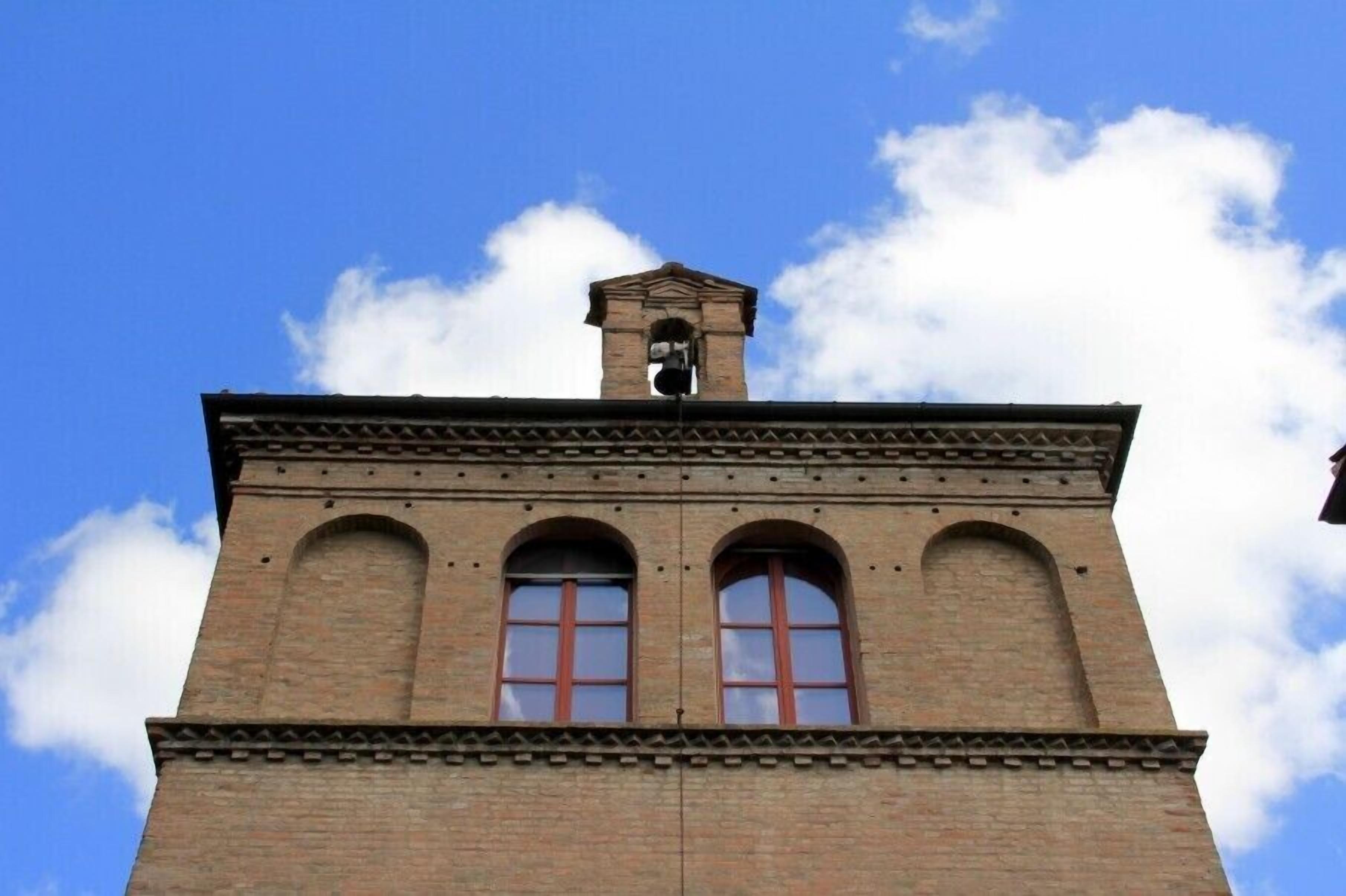 A brick tower with arched windows and a bell at the top.