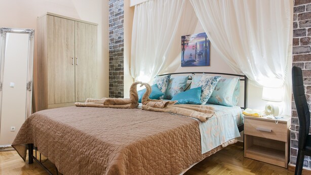 A bedroom with a bed, a nightstand, a wardrobe, and a brick wall. - Athens Cozy Rooms (Athens)