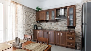A kitchen with wooden cabinets, a built-in stove, and a refrigerator. - Athens Cozy Rooms (Athens)