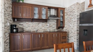 A kitchen with wooden cabinets, a microwave, a coffee maker, and a refrigerator. - Athens Cozy Rooms (Athens)