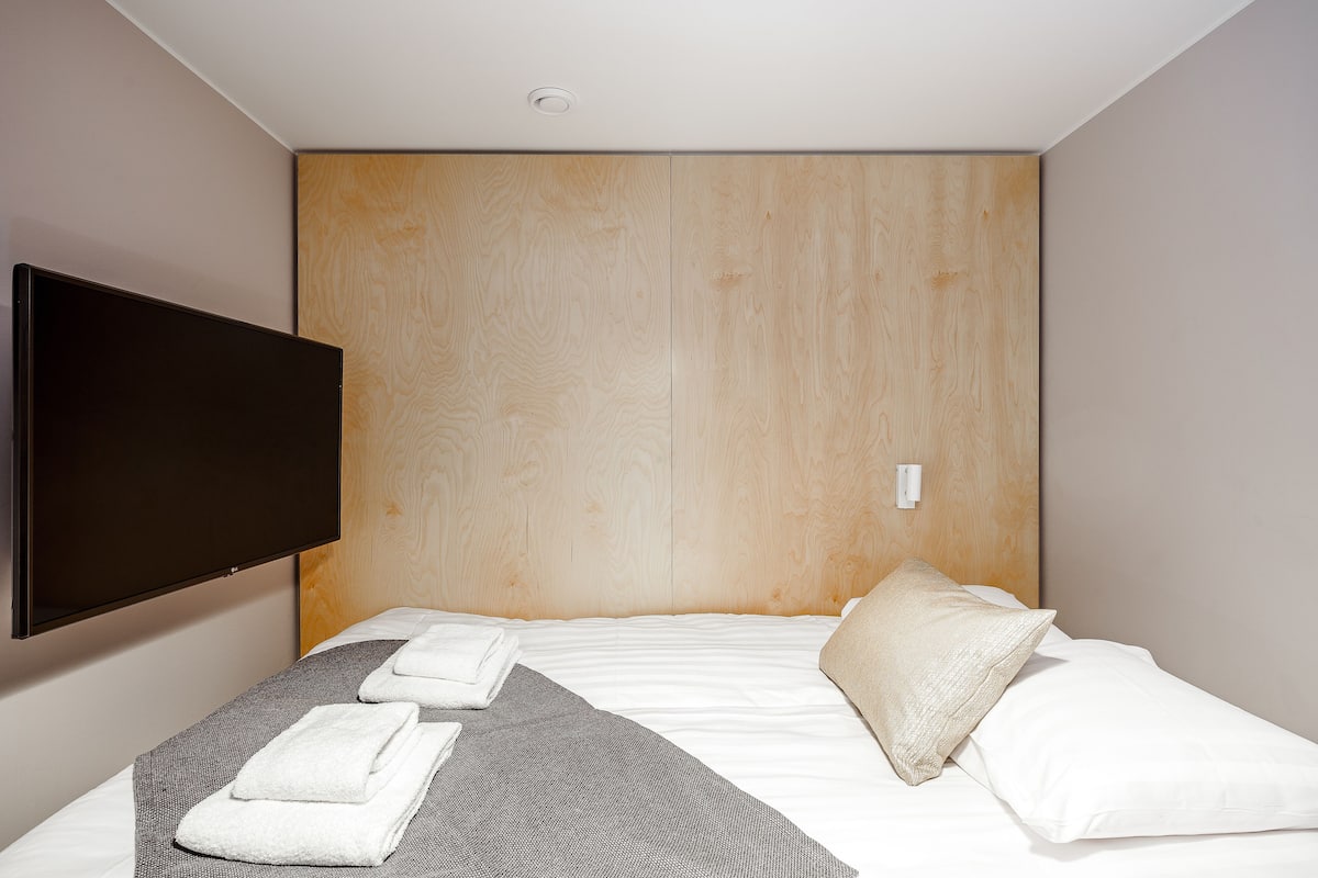Ein Hotelzimmer mit einem großen Bett, einem flachbildfernseher an der Wand und einem hölzernen Kopfteil.