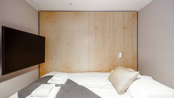 Una habitación de hotel con una cama grande, un televisor de pantalla plana montado en la pared y un cabecero de madera.