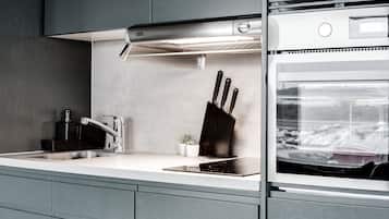 A modern kitchen with a stainless steel range hood, a built-in oven, and a sink.