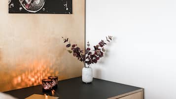 Un escritorio con una computadora portátil, un florero con plantas y dos velas.