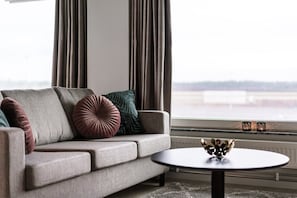 A living room with a sofa, pillows, a coffee table, and a view through a window. - Forenom Aparthotel Arlanda (Arlanda)