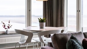A modern dining area with a round table, white chairs, a potted plant, and a pendant light. - Forenom Aparthotel Arlanda (Arlanda)