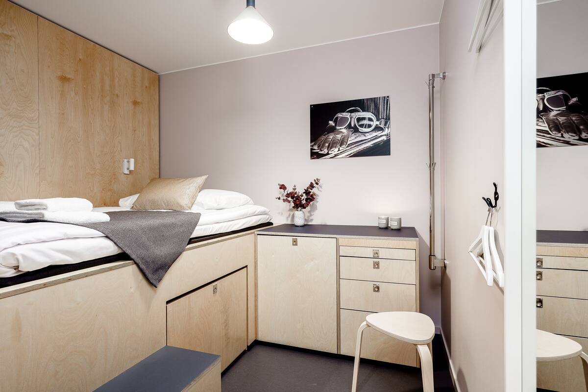 Ein kleines Schlafzimmer mit Bett, Nachttisch und Spiegel.