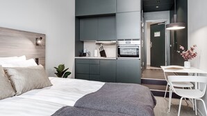 A modern bedroom with a large bed, a small kitchenette, and a dining area with a table and chairs. - Forenom Aparthotel Arlanda (Arlanda)