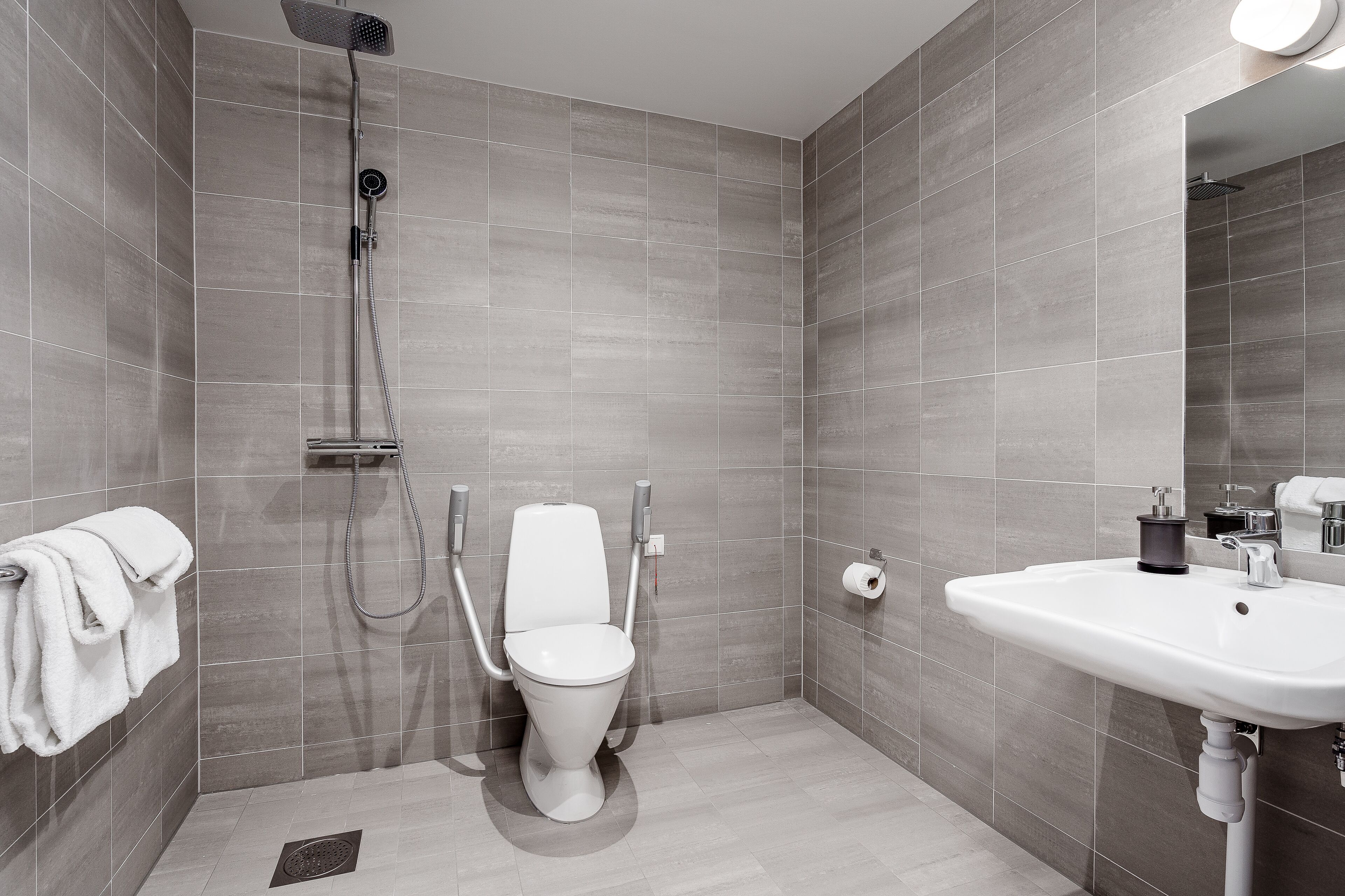 A modern bathroom with a shower, toilet, and sink.