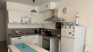 A compact kitchen with white cabinets, a microwave, a toaster, and a refrigerator. - Charming Cottage Near Quend Beach: 2BR, Garden, Parking (Quend)