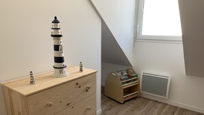 A room with a wooden dresser, a small bookshelf, a window, and a radiator. - Charming Cottage Near Quend Beach: 2BR, Garden, Parking (Quend)