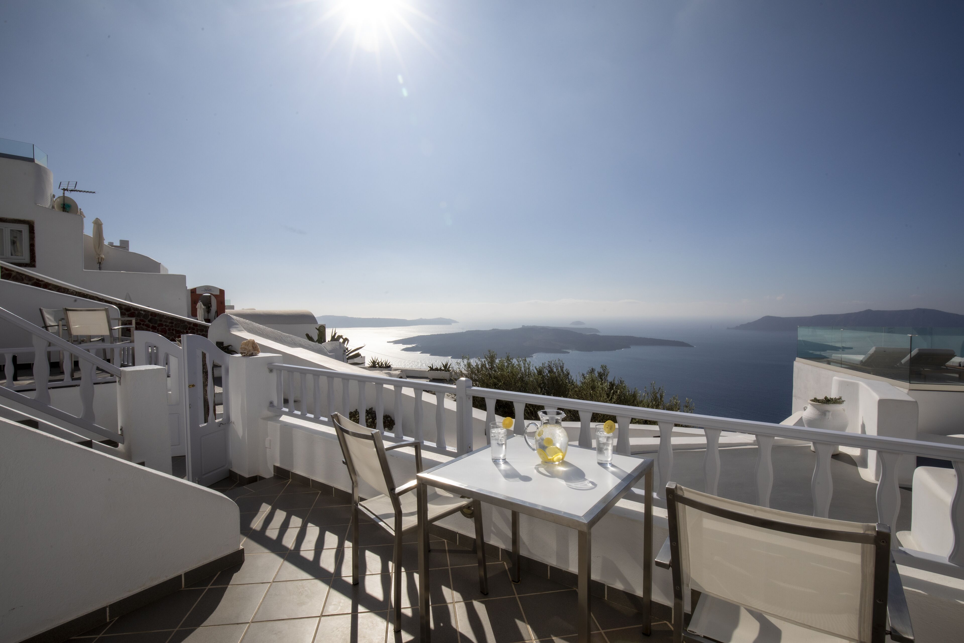 Una terraza con una mesa preparada para dos, con vistas a un paisaje marino y a islas distantes.