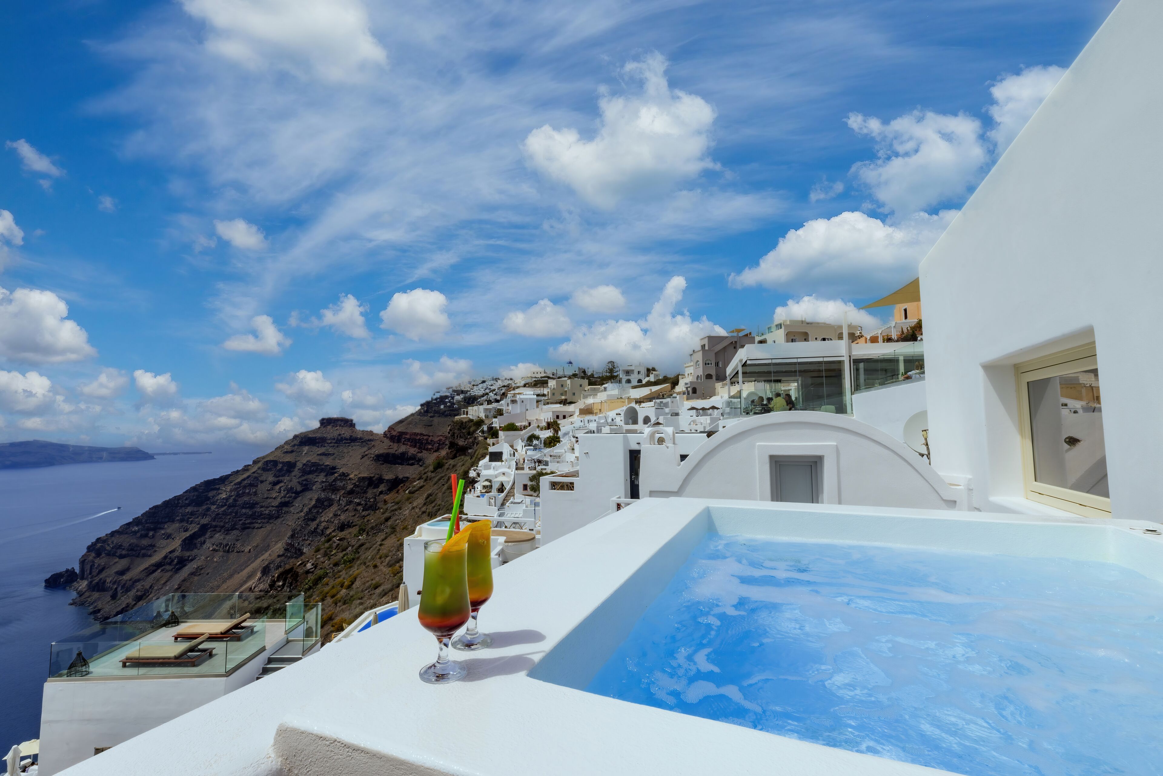 A white building with a pool and a view of the sea.